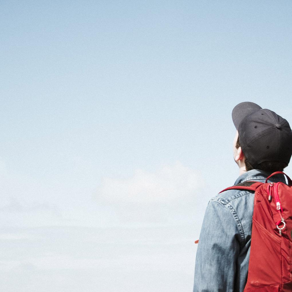 Mann mit Rucksack schaut in den Himmel