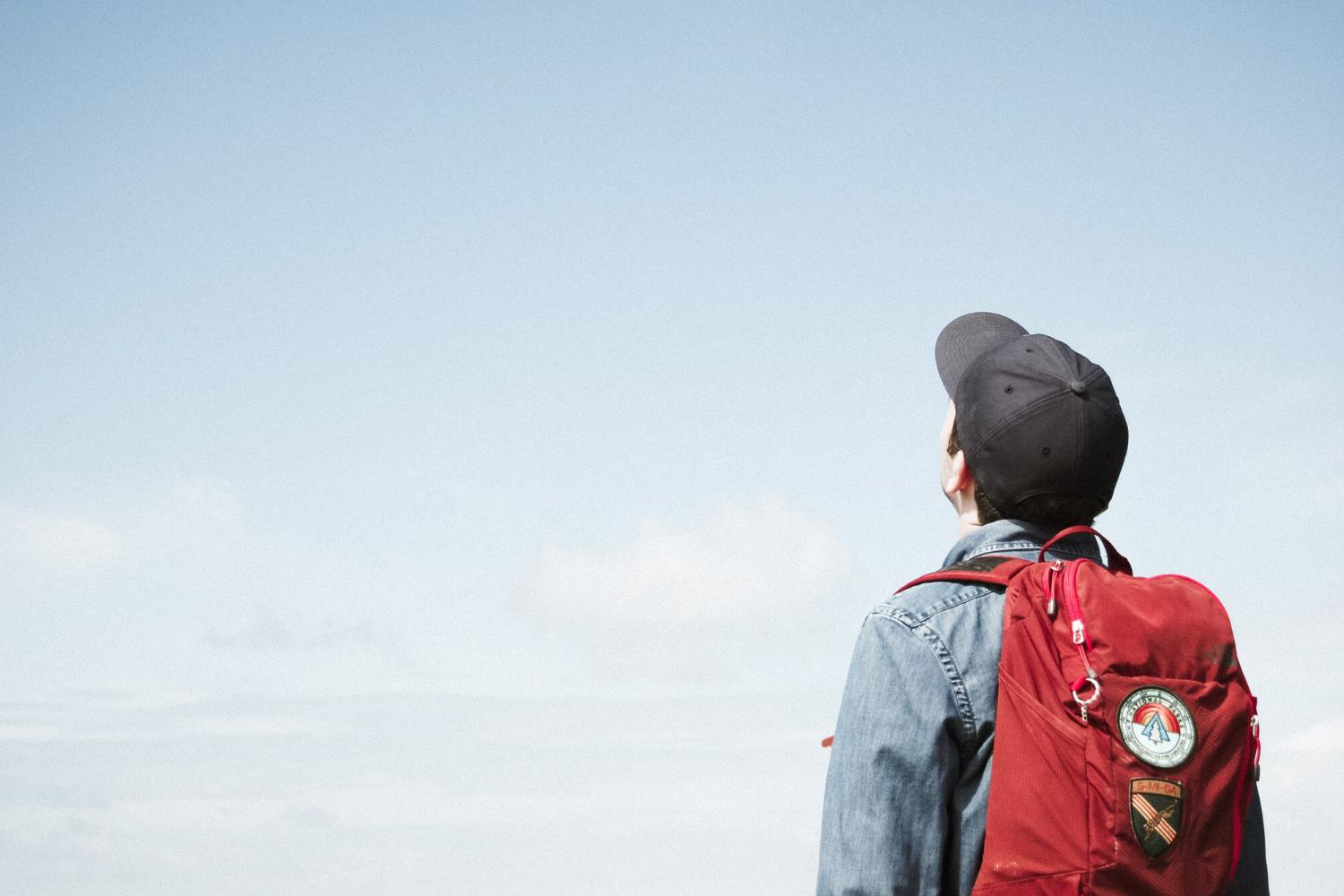 Mann mit Rucksack schaut in den Himmel