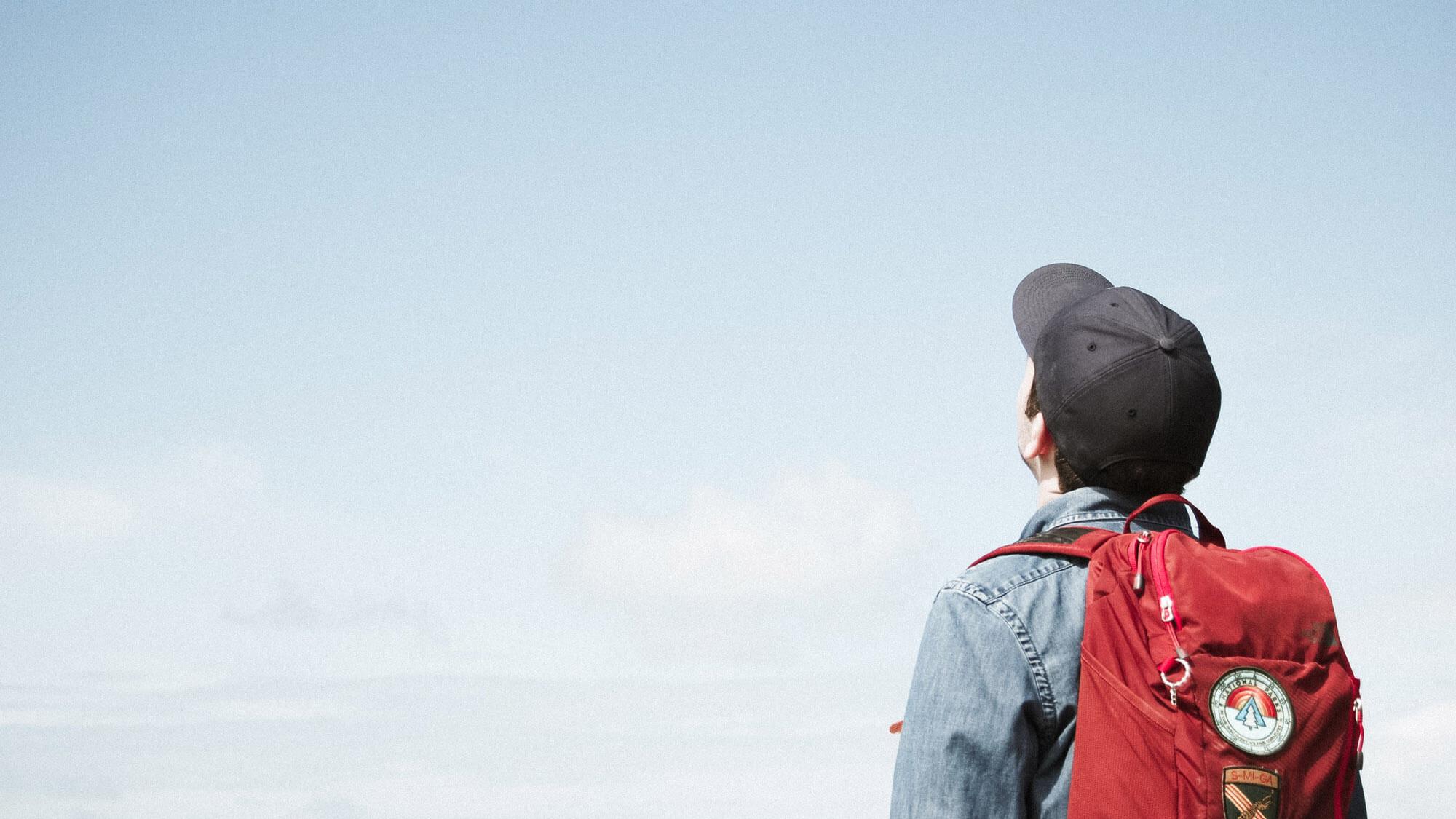 Mann mit Rucksack schaut in den Himmel