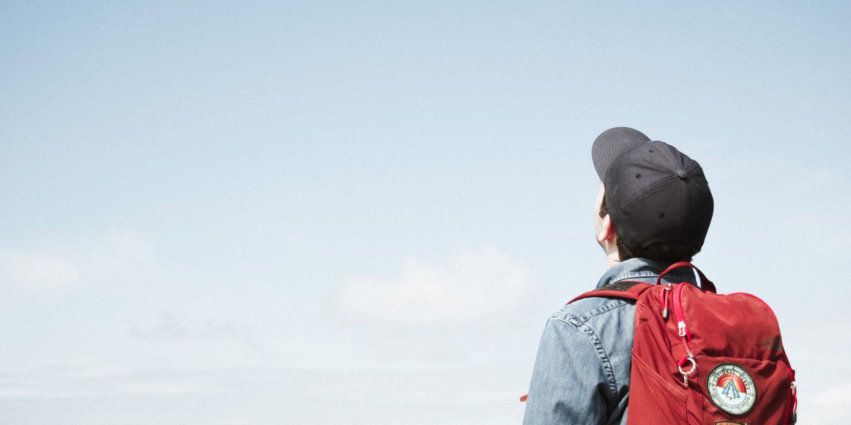 Mann mit Rucksack schaut in den Himmel